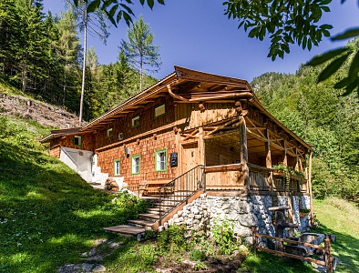 Außenansicht der Talsenalm aus Holz inmitten grüner Natur