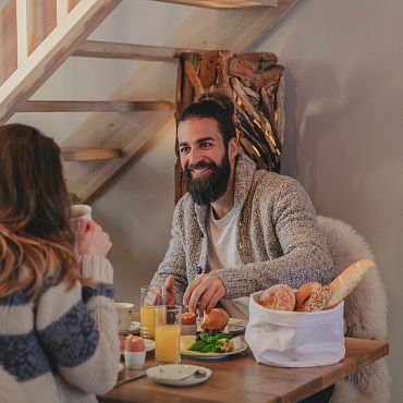 Ein Paar genießt ein Frühstück in einem gemütlichen Essbereich mit frischen Brötchen und Orangensaft