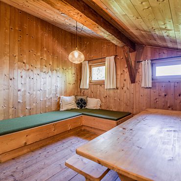Ein gemütlicher Sitzbereich mit Holzwänden und grünem Polster in der Talsenalm